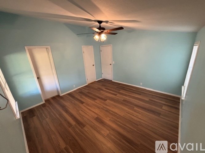 A room with a ceiling fan and wooden flooring.