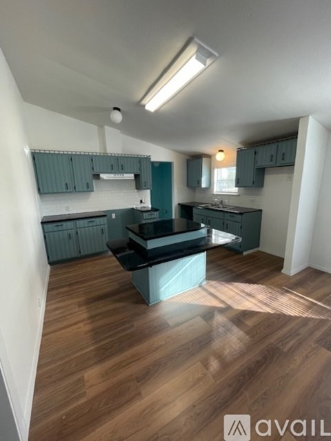 A kitchen with a black countertop and wooden flooring.