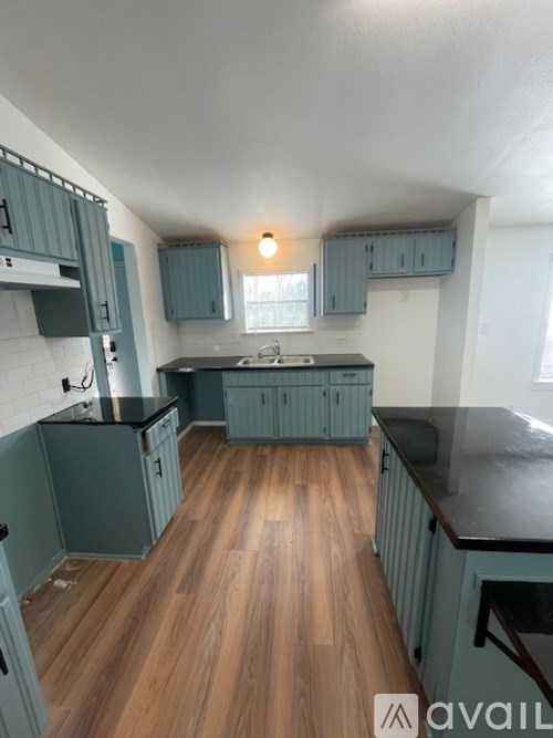 A kitchen with wooden floors and green cabinets.