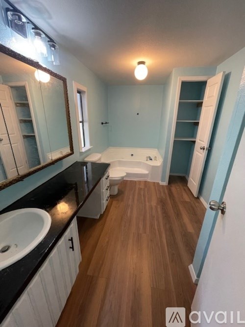 A bathroom with a wooden floor and a white sink.