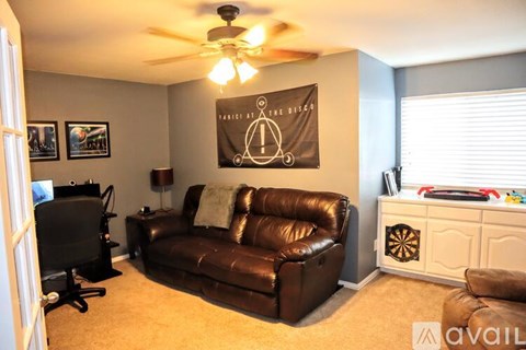 A living room with a brown leather couch and a TV.