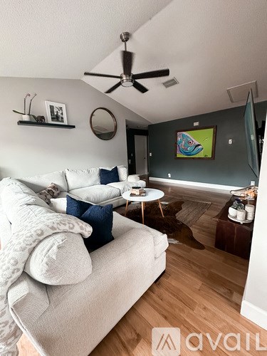 A living room with a white couch and a ceiling fan.