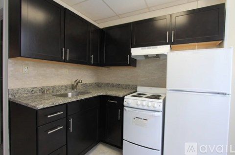A kitchen with black cabinets and a white refrigerator.
