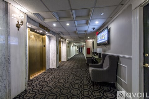 A hallway with a patterned carpet and a television mounted on the wall.