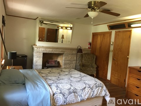 A bedroom with a bed, dresser, and a fireplace.