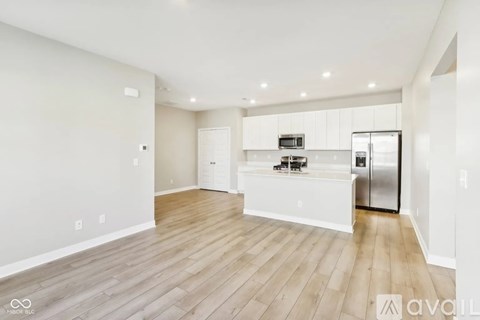 A spacious kitchen with white cabinets and a wooden floor.