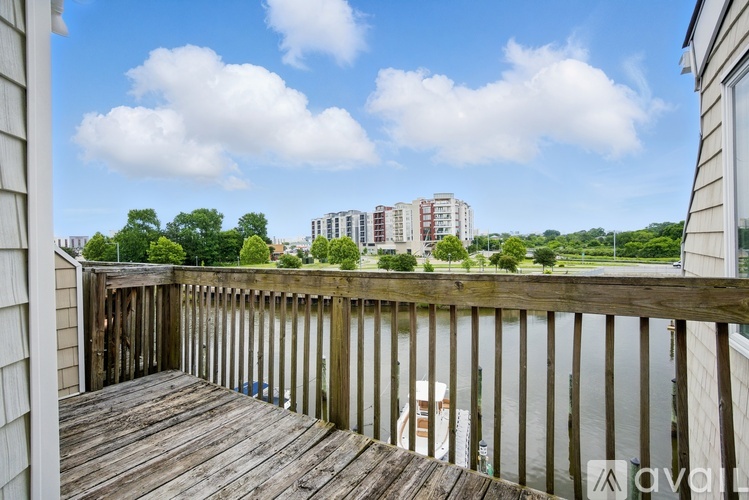 A wooden deck overlooks a body of water with buildings in the distance.