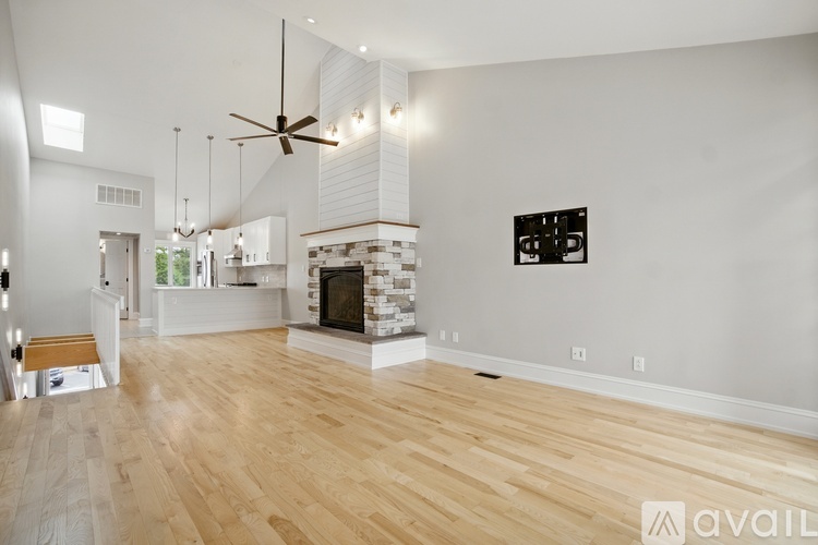 A spacious living room with a fireplace and a fan.