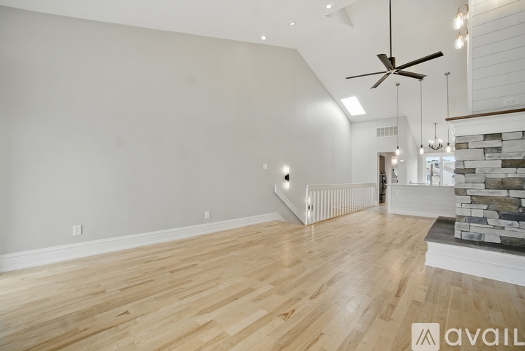 A spacious room with wooden flooring and a ceiling fan.
