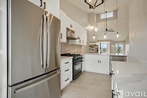 A modern kitchen with a stainless steel refrigerator and white cabinets.