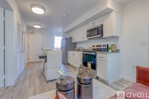 A modern kitchen with white cabinets and a wooden floor.