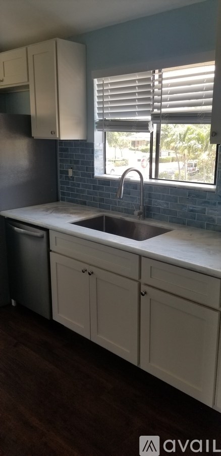 A kitchen with white cabinets and a blue tile backsplash.
