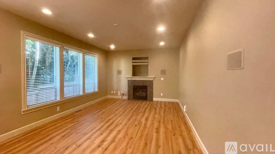 A spacious room with wooden flooring and a fireplace.