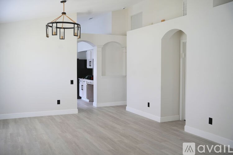 A room with a chandelier and arched doorways.