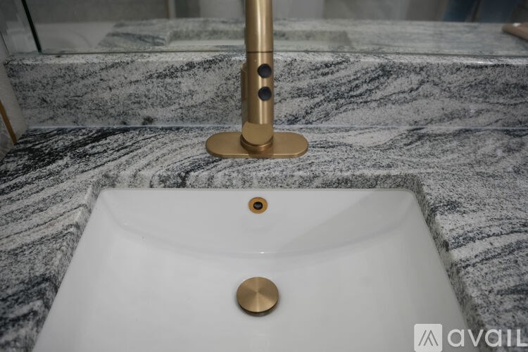 A bathroom sink with a gold faucet and a marble countertop.