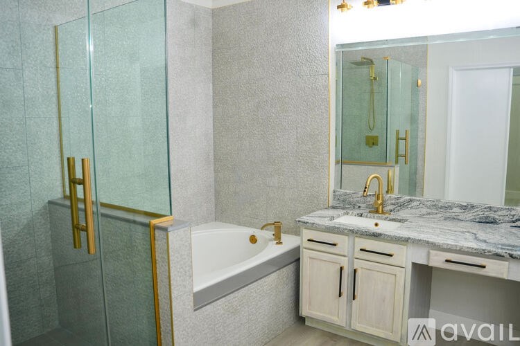 A bathroom with a marble countertop and a glass shower enclosure.