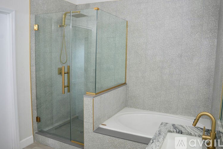 A bathroom with a glass shower enclosure and a white bathtub.