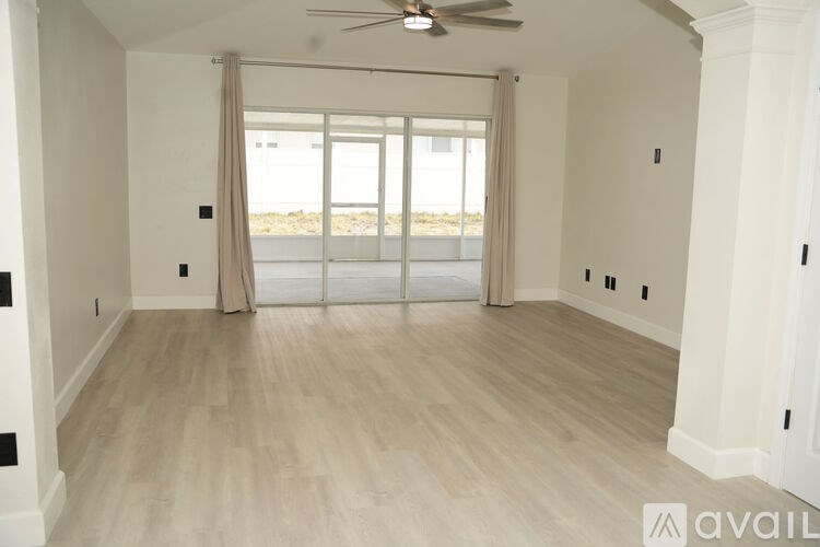 A spacious room with a ceiling fan and sliding glass doors leading to a beach.