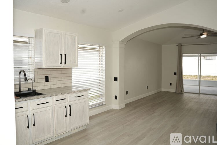 A kitchen with white cabinets and a black countertop.