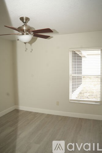A room with a ceiling fan and a window with blinds.
