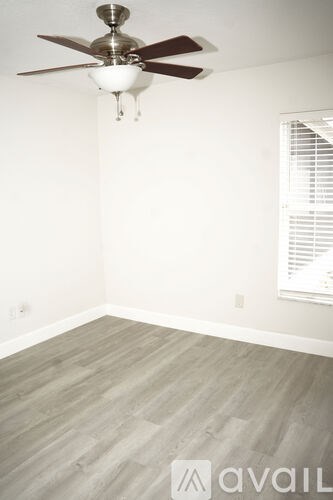 A room with a ceiling fan and wooden flooring.