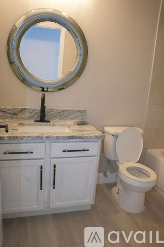 A bathroom with a toilet, sink and mirror.