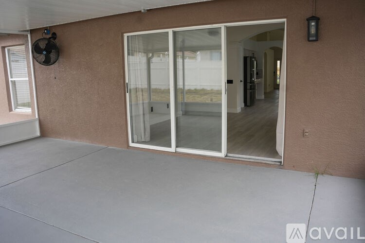 A patio area with a sliding glass door leading to a backyard.