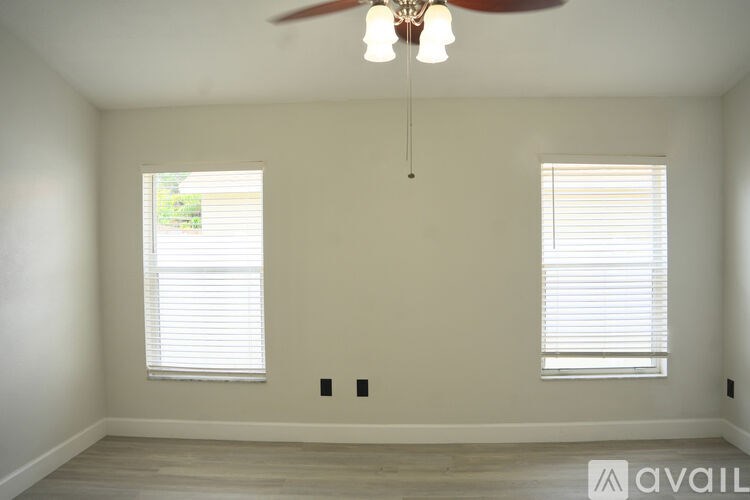A room with a fan and two windows.