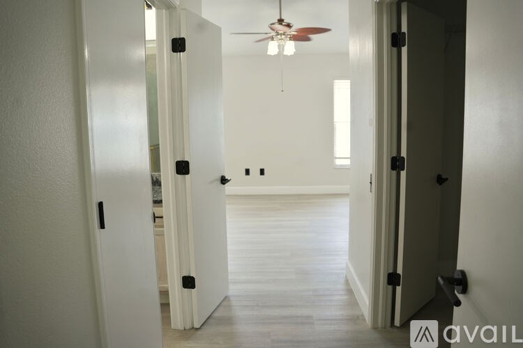 A hallway with a fan and doors on both sides.