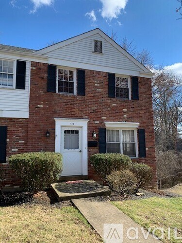 A brick house with a white door and black shutters.