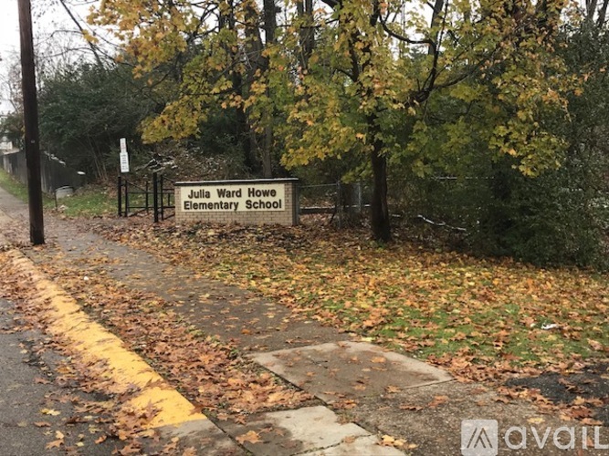 A sign for Julia Ward Howe Elementary School is displayed in front of a fence and trees.