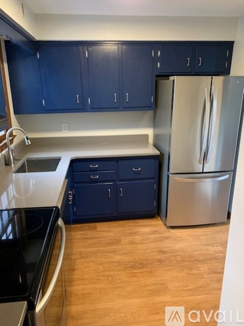 A kitchen with blue cabinets and a stainless steel refrigerator.
