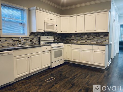 A kitchen with white cabinets and a stone backsplash.