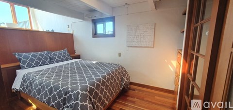 A wooden bedroom with a bed, desk, and chair.