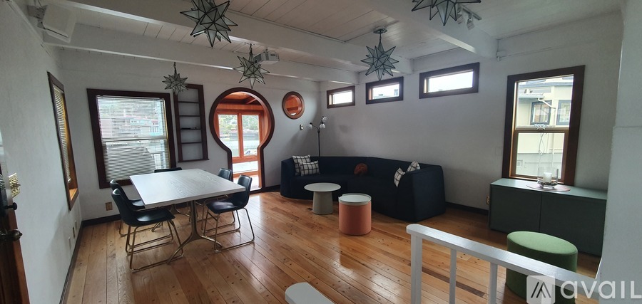 A living room with a black couch and a wooden floor.