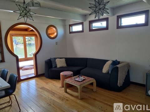 A living room with a black couch and a wooden floor.