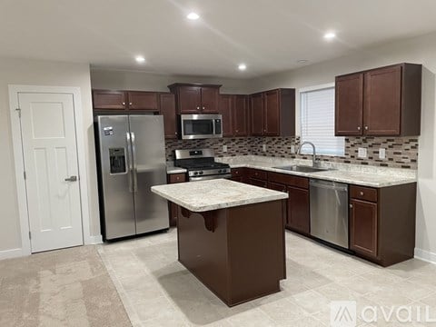 A kitchen with brown cabinets and a marble countertop.