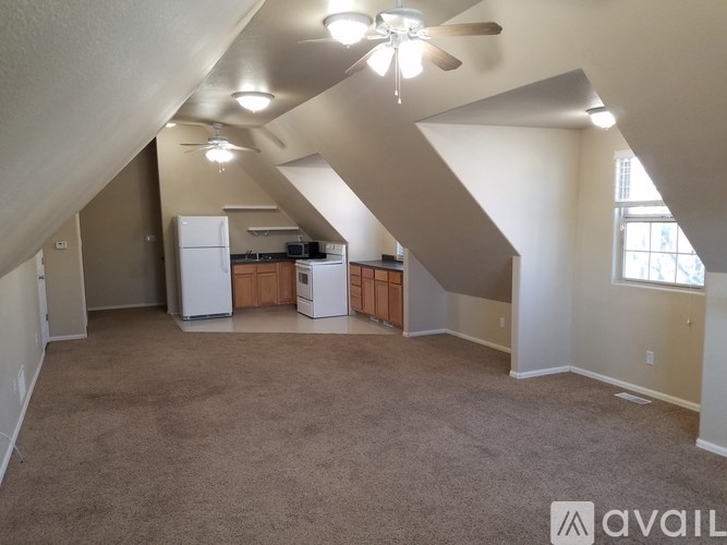 A spacious room with a carpeted floor and a ceiling fan.