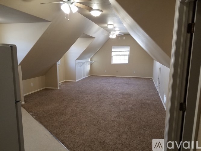 A room with a carpeted floor and a window with a white frame.