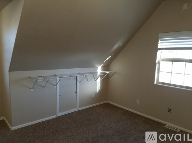 A room with a carpeted floor and a window with blinds.