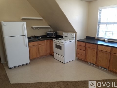 A kitchen with a white fridge, white stove and wooden cabinets.