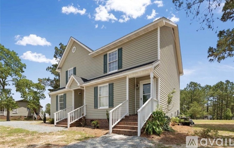 A house with a porch and a green lawn in front.