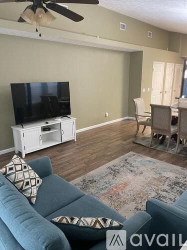A living room with a blue couch and a television on a white stand.