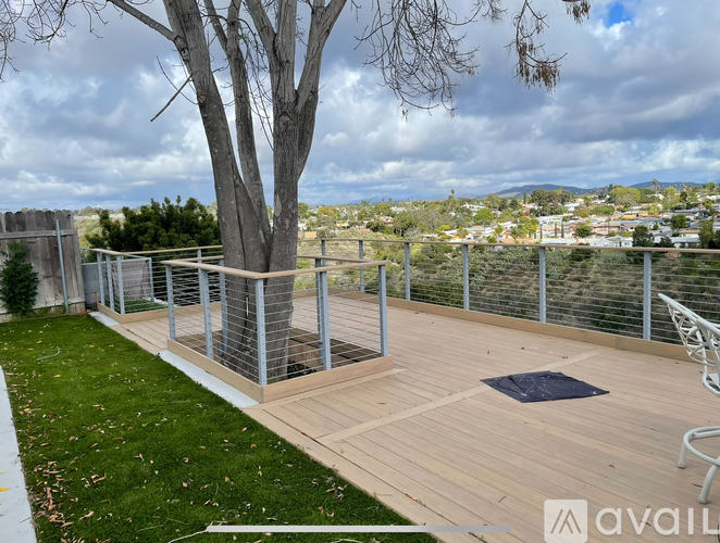 A wooden deck with a metal railing and a tree in the foreground.