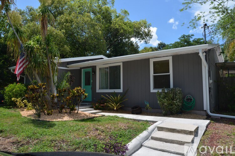 A grey house with a green door and a flag on the left.