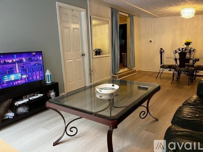 A living room with a glass coffee table and a television on the left side.