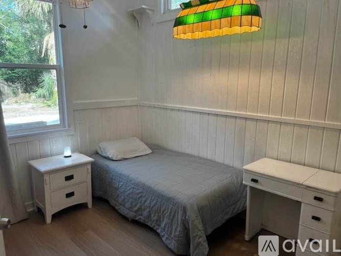 A bedroom with a bed, desk, and lamp.