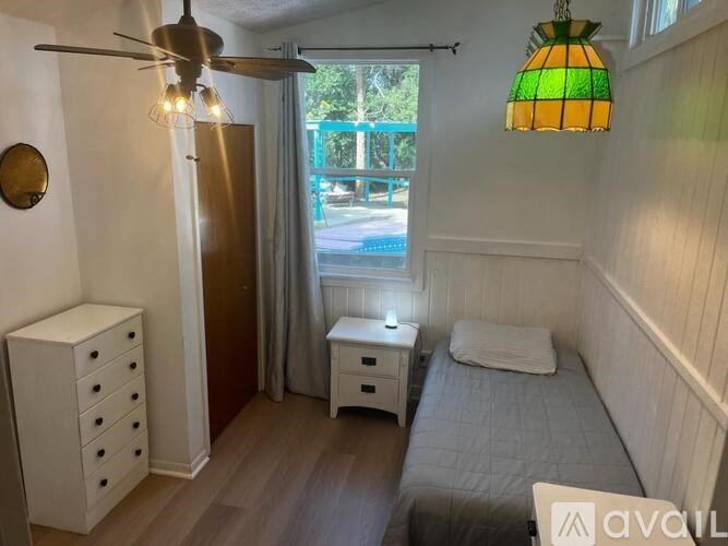 A room with a bed, a dresser, and a ceiling fan.