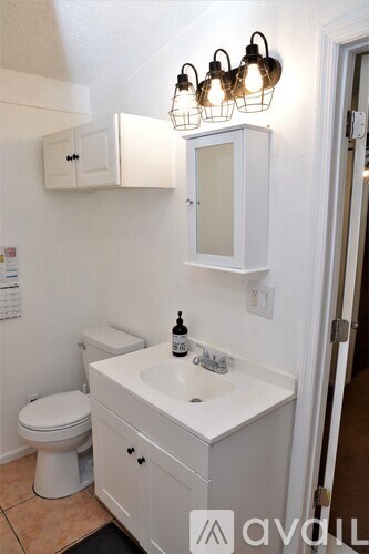 A white bathroom with a toilet, sink, and mirror.