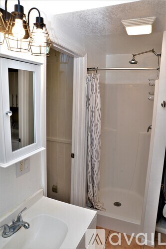 A bathroom with a white sink and a shower with a glass door.